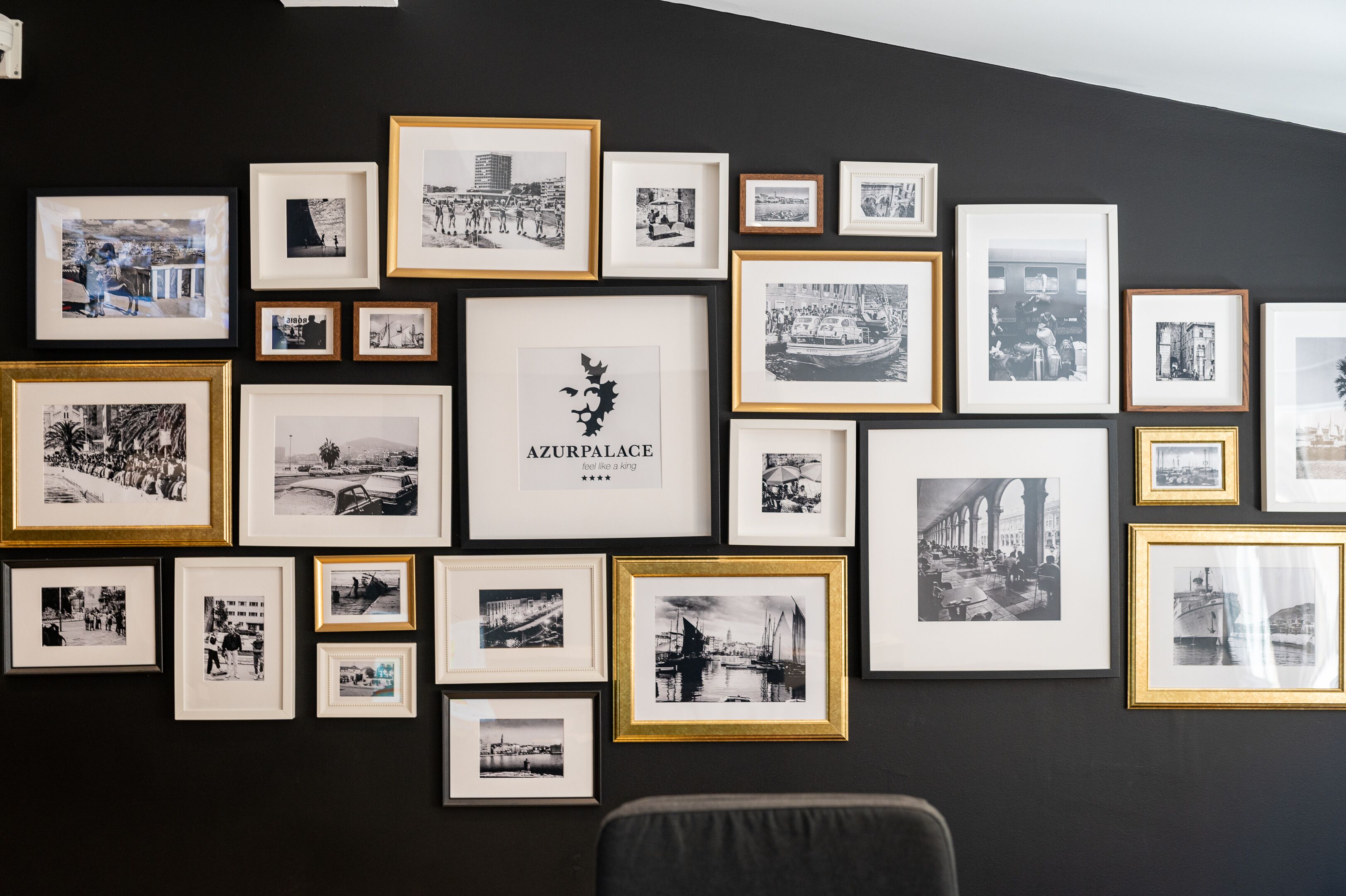 En væg med flere indrammede sort-hvide fotografier af forskellige motiver, herunder et markant billede med teksten "AZURPALACE".