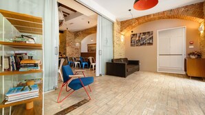A modern interior with a brick wall, a wooden bookshelf, a blue chair, and a black sofa. - Azur Palace Luxury Rooms (Split)