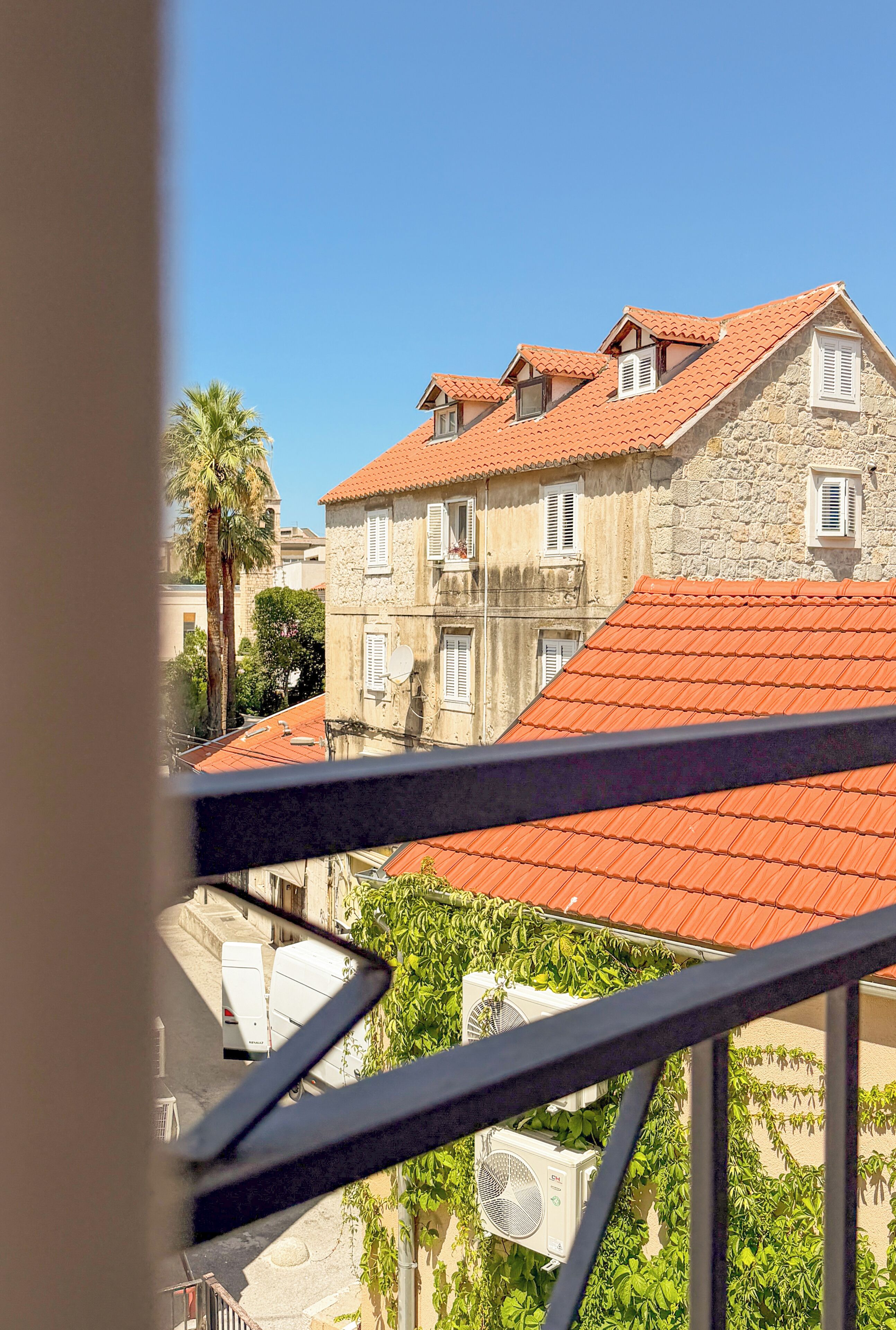 A building with a red-tiled roof and stone walls, featuring multiple windows and balconies.
