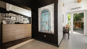 A reception area with a wall-mounted photo display, a wooden reception desk, and a large painting of a blue door. - Azur Palace Luxury Rooms (Split)