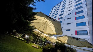 Un hôtel doté de nombreuses chambres, de parasols installés à l’extérieur et d’un jardin bien entretenu.