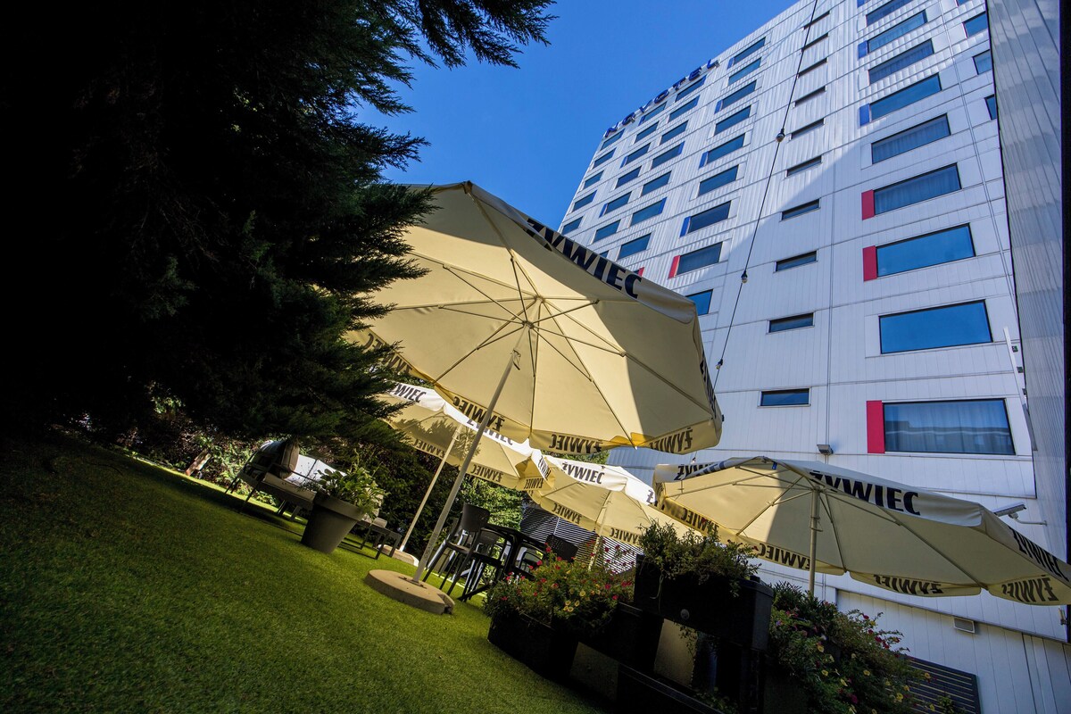 A hotel with multiple rooms, outdoor umbrellas, and a well-maintained garden.