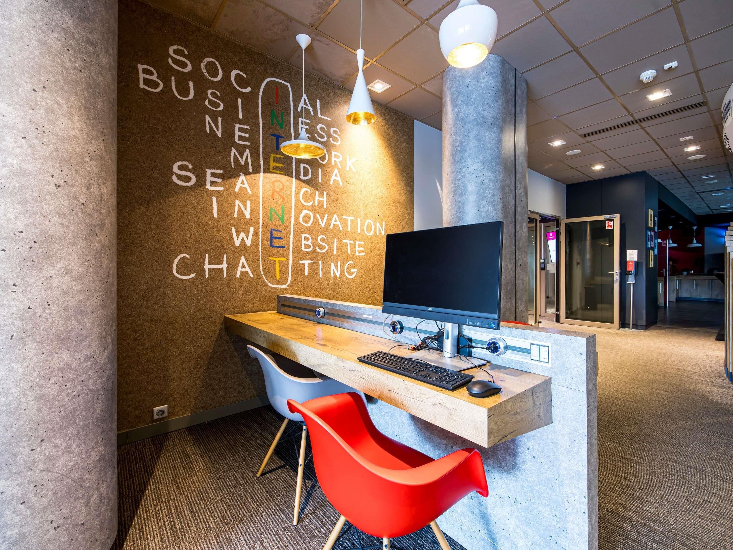 Un comptoir d’accueil moderne, équipé d’un ordinateur, d’une chaise rouge et d’un mur orné de texte.