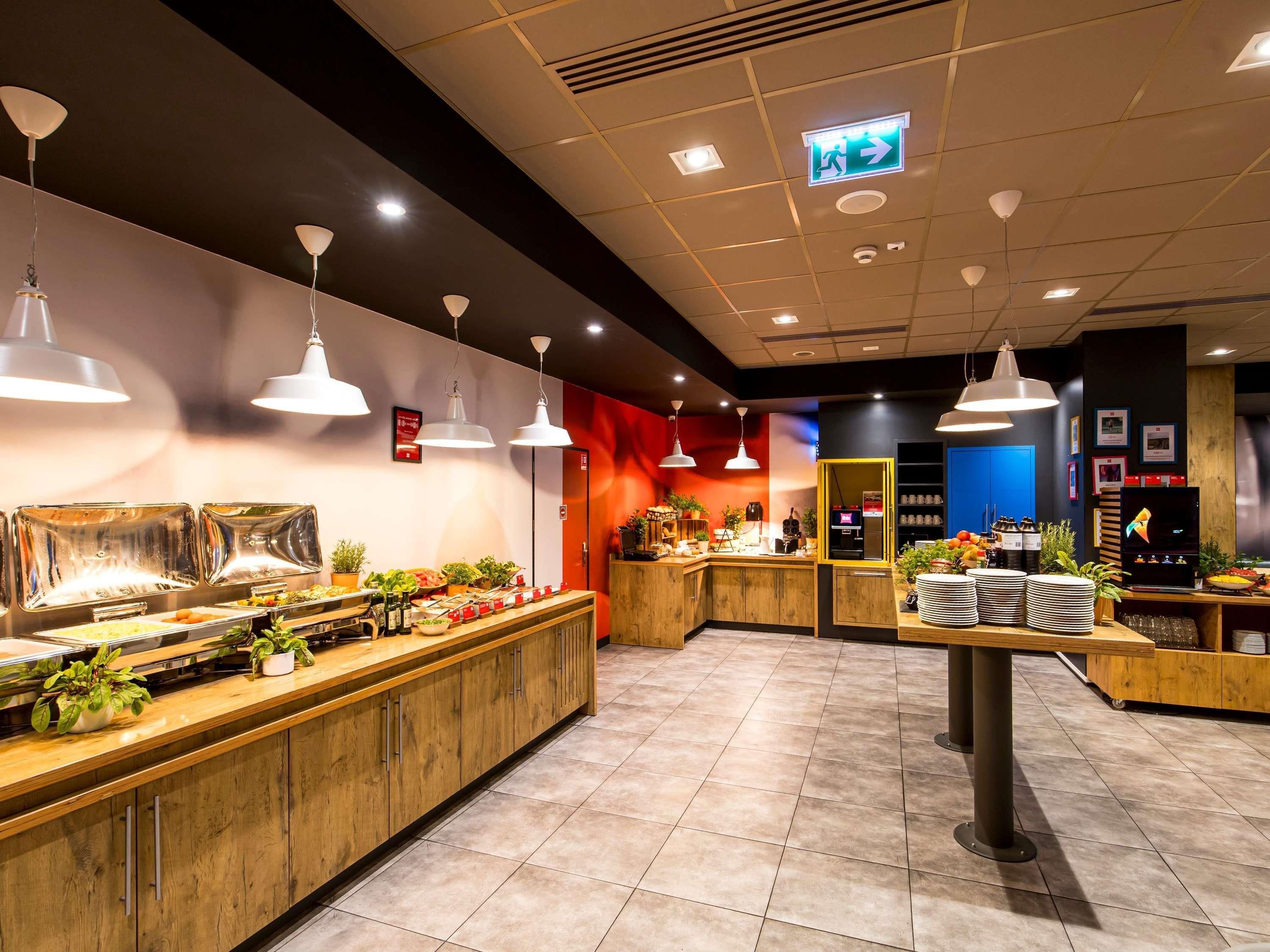 A buffet area with multiple food stations, overhead lighting, and a counter with various items.