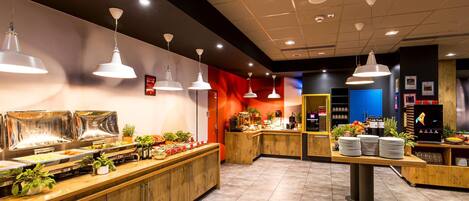 A buffet area with multiple food stations, overhead lighting, and a counter with various items.