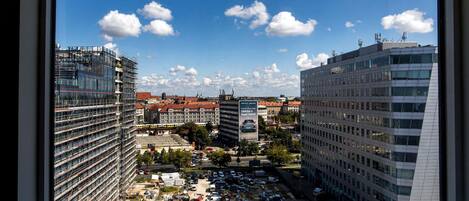 A cityscape with modern buildings, a clear sky, and a billboard advertising a car.