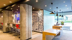 Un espace d’accueil moderne comprenant un comptoir de réception, des sièges et un mur décoré d’une fresque.