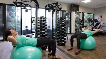 Un gimnasio con equipo de ejercicio, ventanas amplias y una cinta de correr.