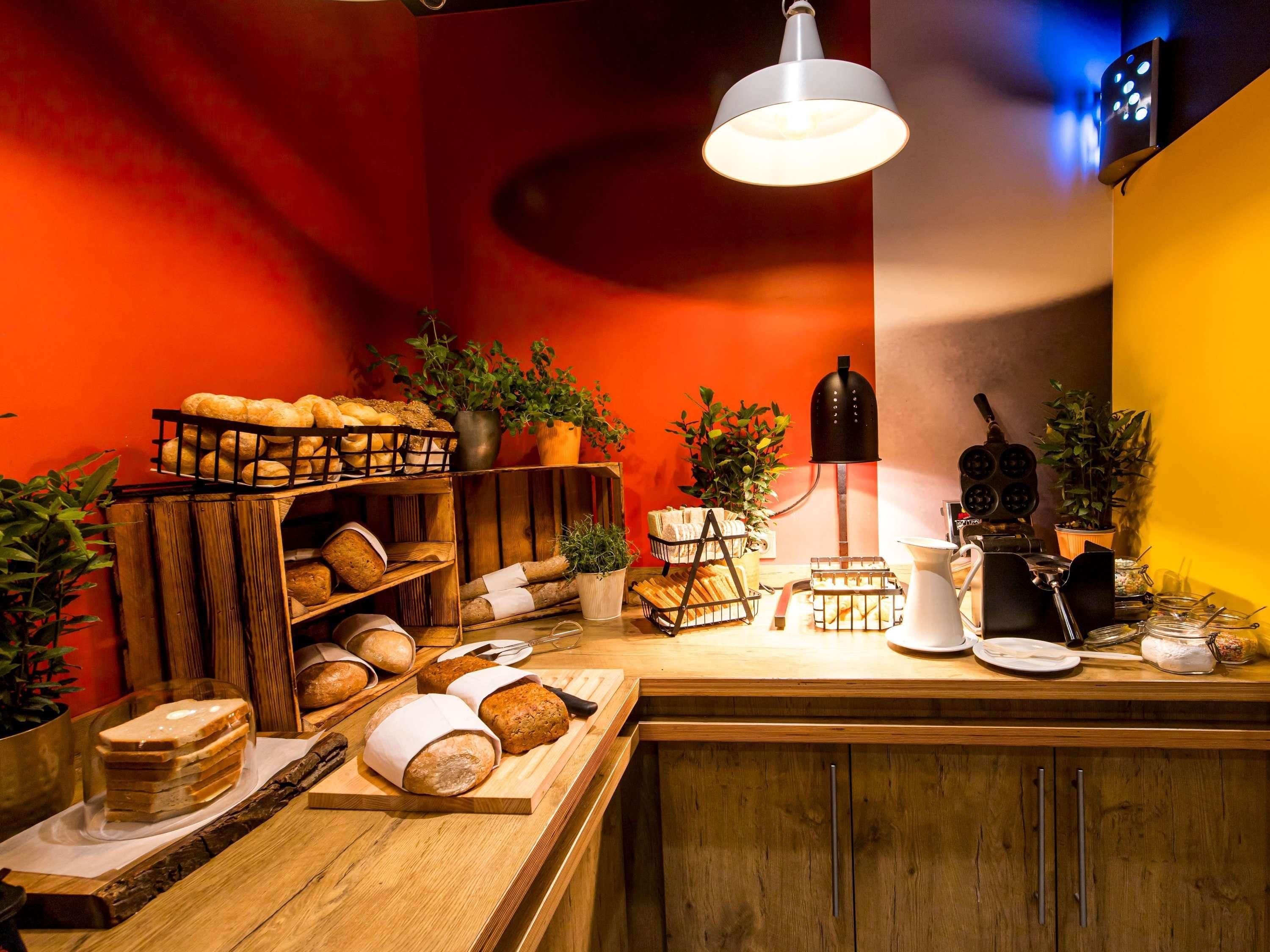 A bakery counter with various breads and pastries, a coffee machine, and a hanging light fixture.