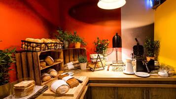 A bakery counter with various breads and pastries, a coffee machine, and a hanging light fixture.