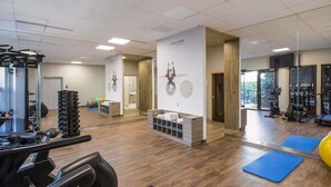 Une salle de sport équipée de matériel d’exercice, un comptoir d’accueil et un miroir.