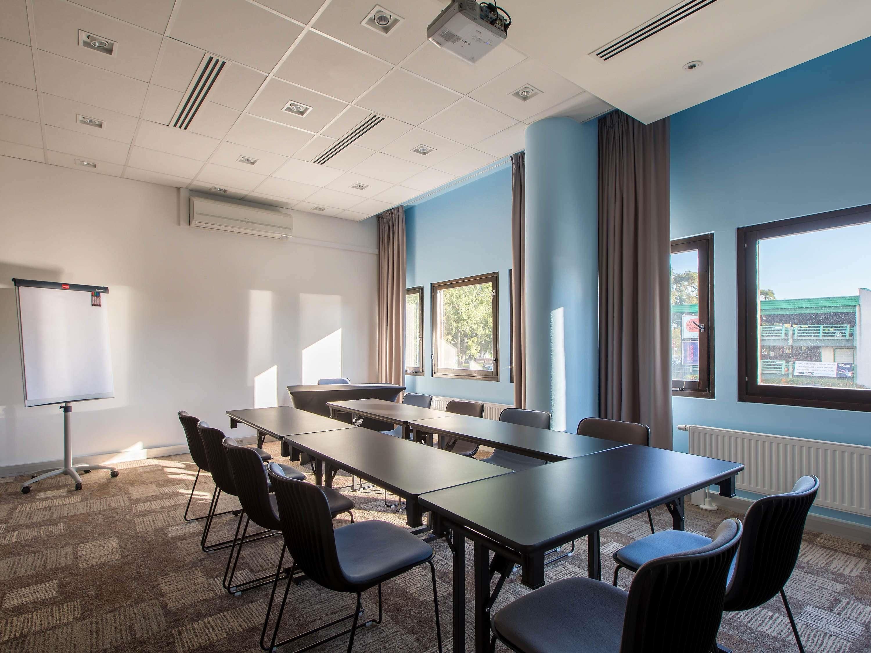 A conference room with a long table, chairs, a whiteboard, and large windows.