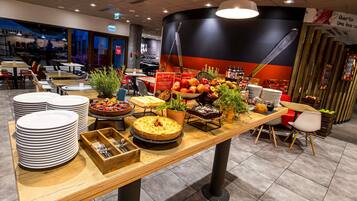 A buffet setup with various food items and a seating area with tables and chairs.