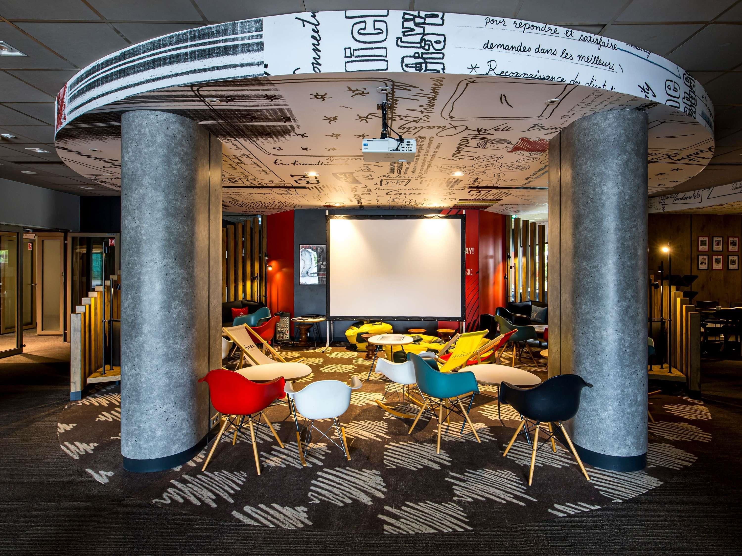 A modern lounge area with a curved ceiling, comfortable seating, and a large screen for presentations.