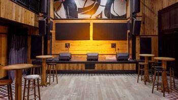 A bar area with multiple seating options, including bar stools and chairs, and a central wooden table with a decorative bowl. at The Barnett - JDV by Hyatt