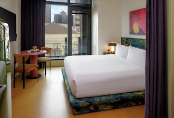 A cozy room with wooden walls and a checkered floor, featuring a stage with speakers and a large abstract painting above. at The Barnett - JDV by Hyatt