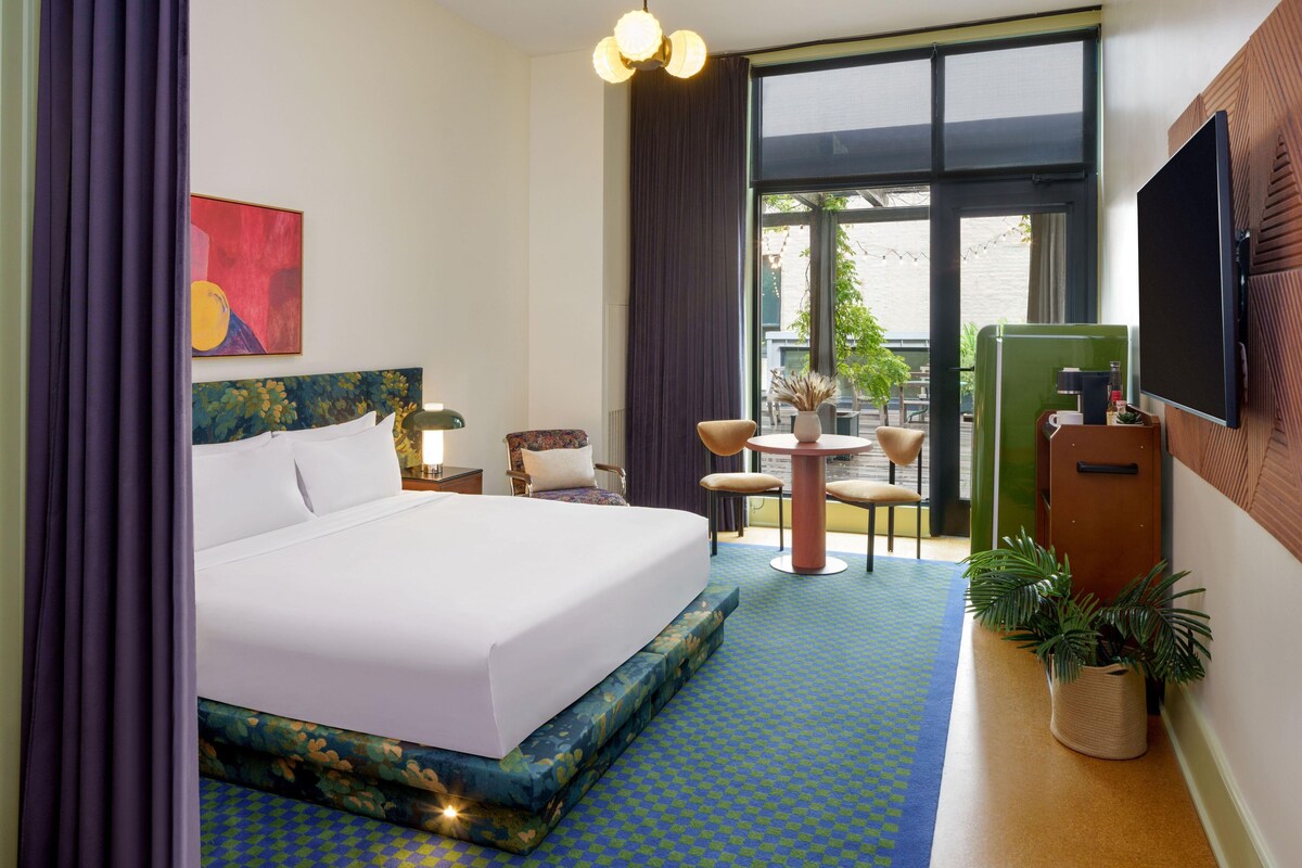 Een hotelkamer met een bed, een bureau, een stoel, een televisie en een raam.