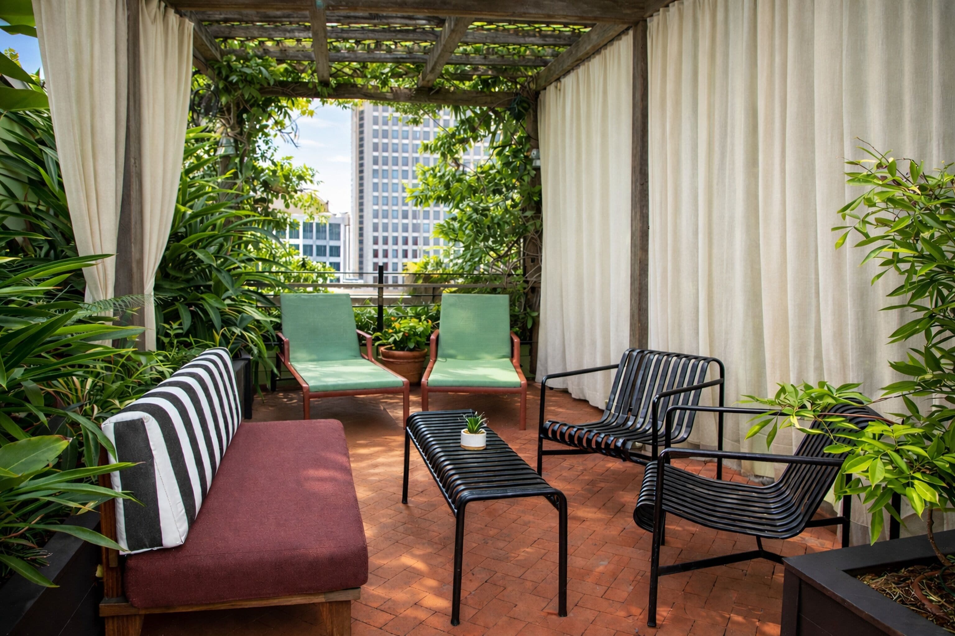 A covered patio area with a sofa, two chairs, a small table, and potted plants.