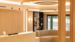 A modern reception area with a curved sofa, wooden paneling, and a marble floor.