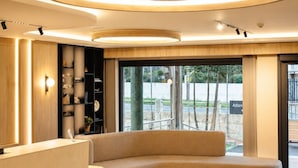 Un hall d’entrée moderne doté d’un espace salon aux lignes courbes, d’un comptoir d’accueil et d’une grande fenêtre offrant une vue sur l’extérieur.