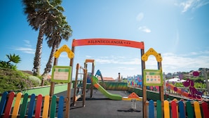 A playground with a slide and climbing structures, surrounded by a colorful fence. - Hotel Atlántico Sanxenxo (Sanxenxo)