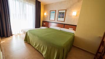 A hotel room with a large bed, two wall-mounted lights, and a window with curtains.