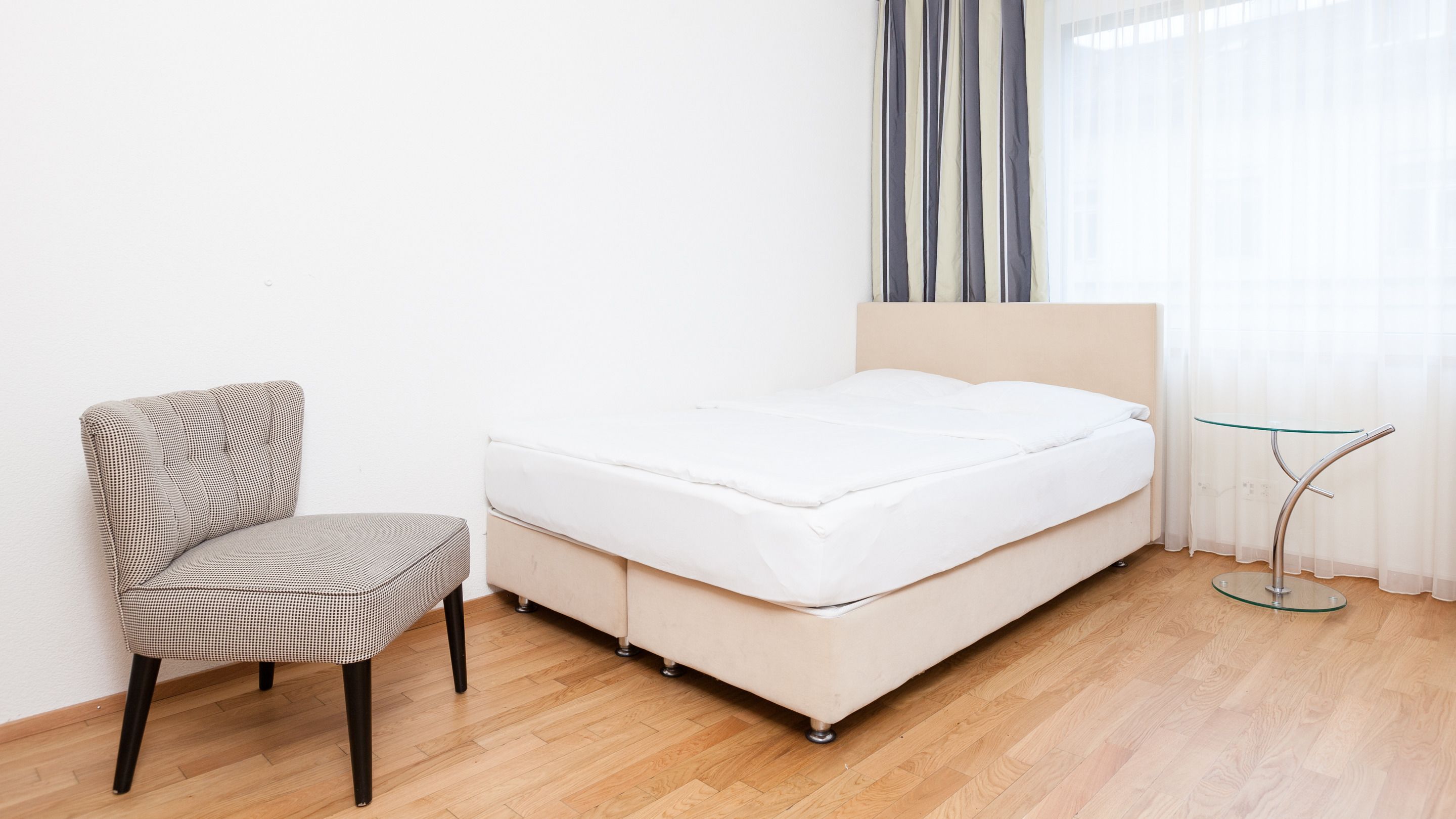 A bedroom with a bed, a chair, and a small table.