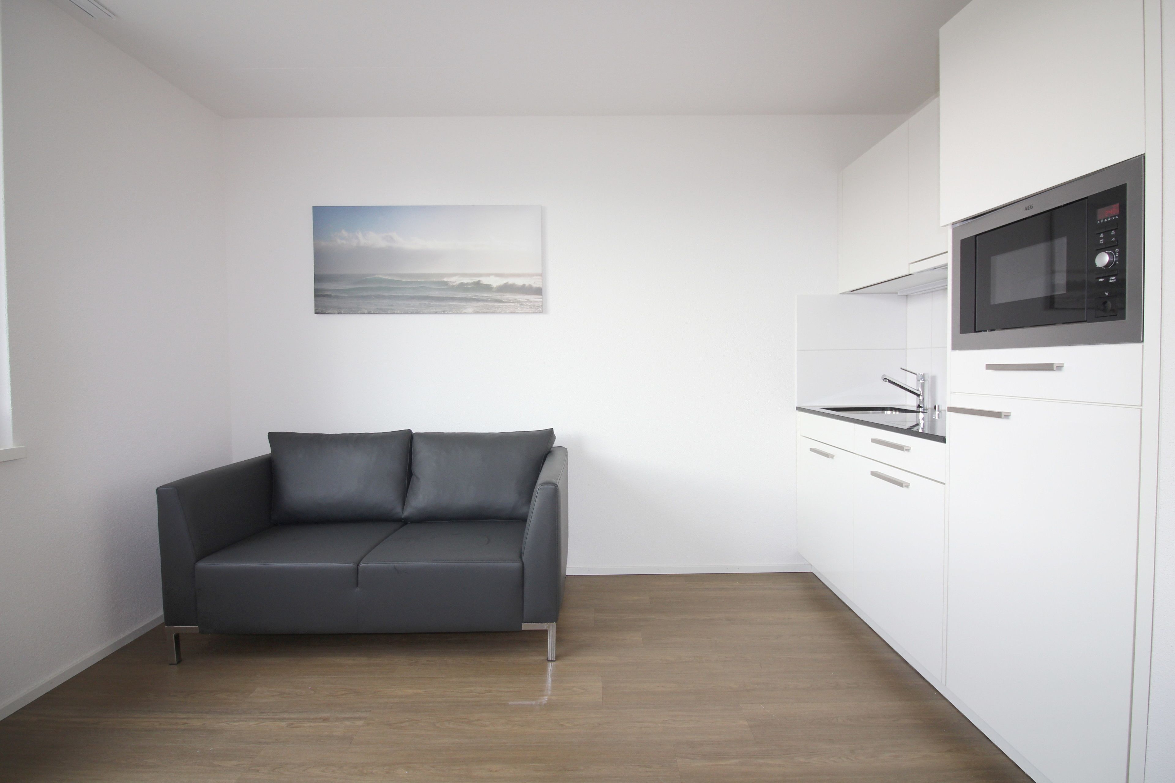A modern kitchen with white cabinets and a built-in microwave.