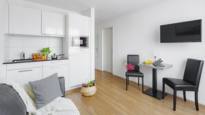 A modern kitchen with white cabinets, a microwave, and a small dining area with a table and chairs.