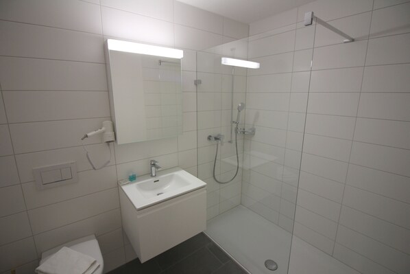 Ein modernes Badezimmer mit Waschbecken, Spiegel und Duschkabine aus Glas.