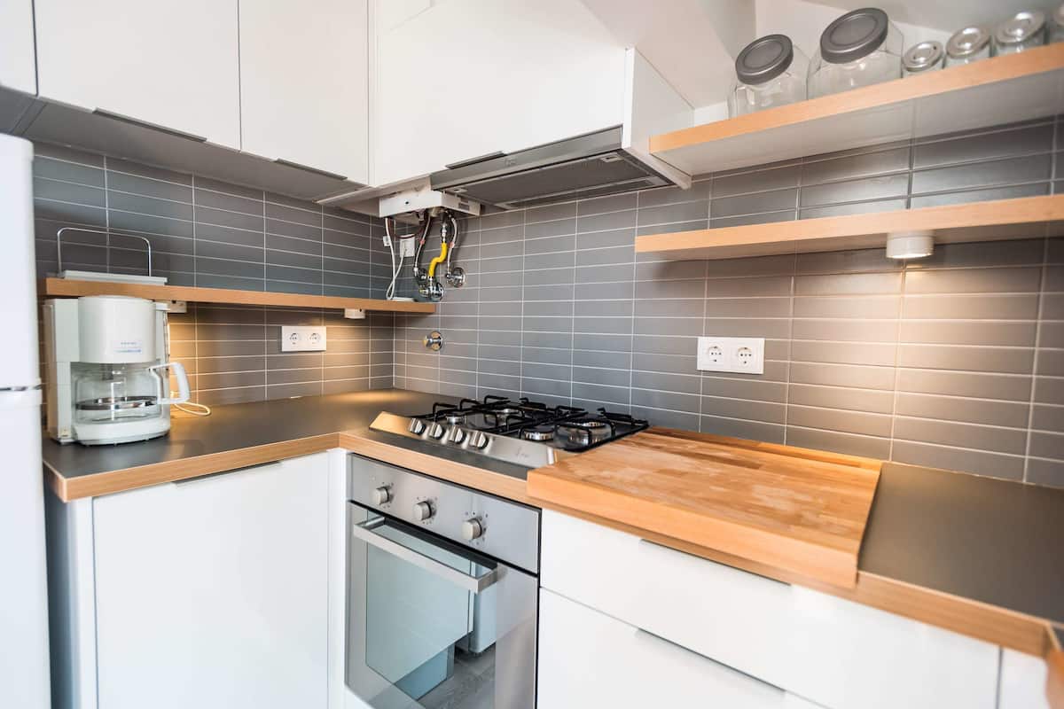 A modern kitchen with a gas stove, oven, and coffee maker.