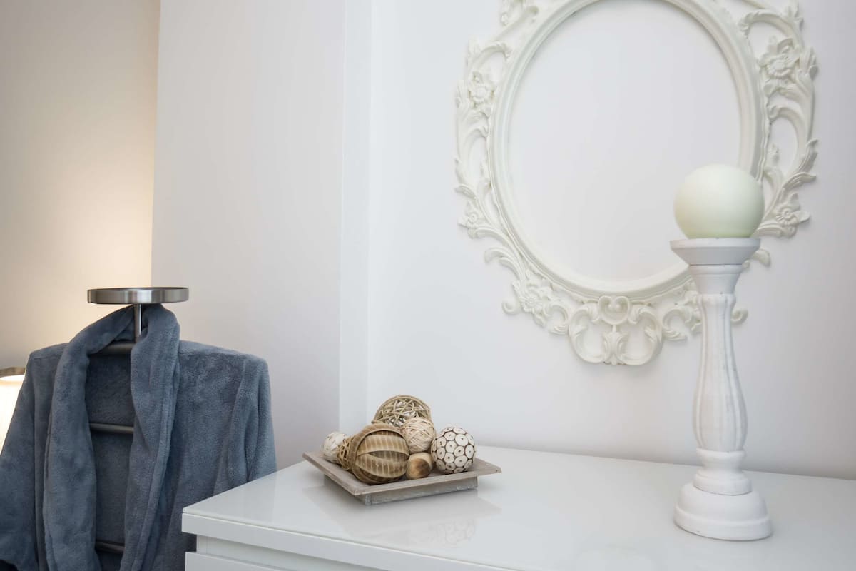 A bathroom with a white vanity, a mirror with an ornate frame, and a towel rack with a blue towel.