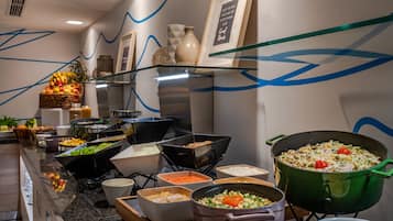 Buffet com diversos alimentos e uma grande panela de massa.