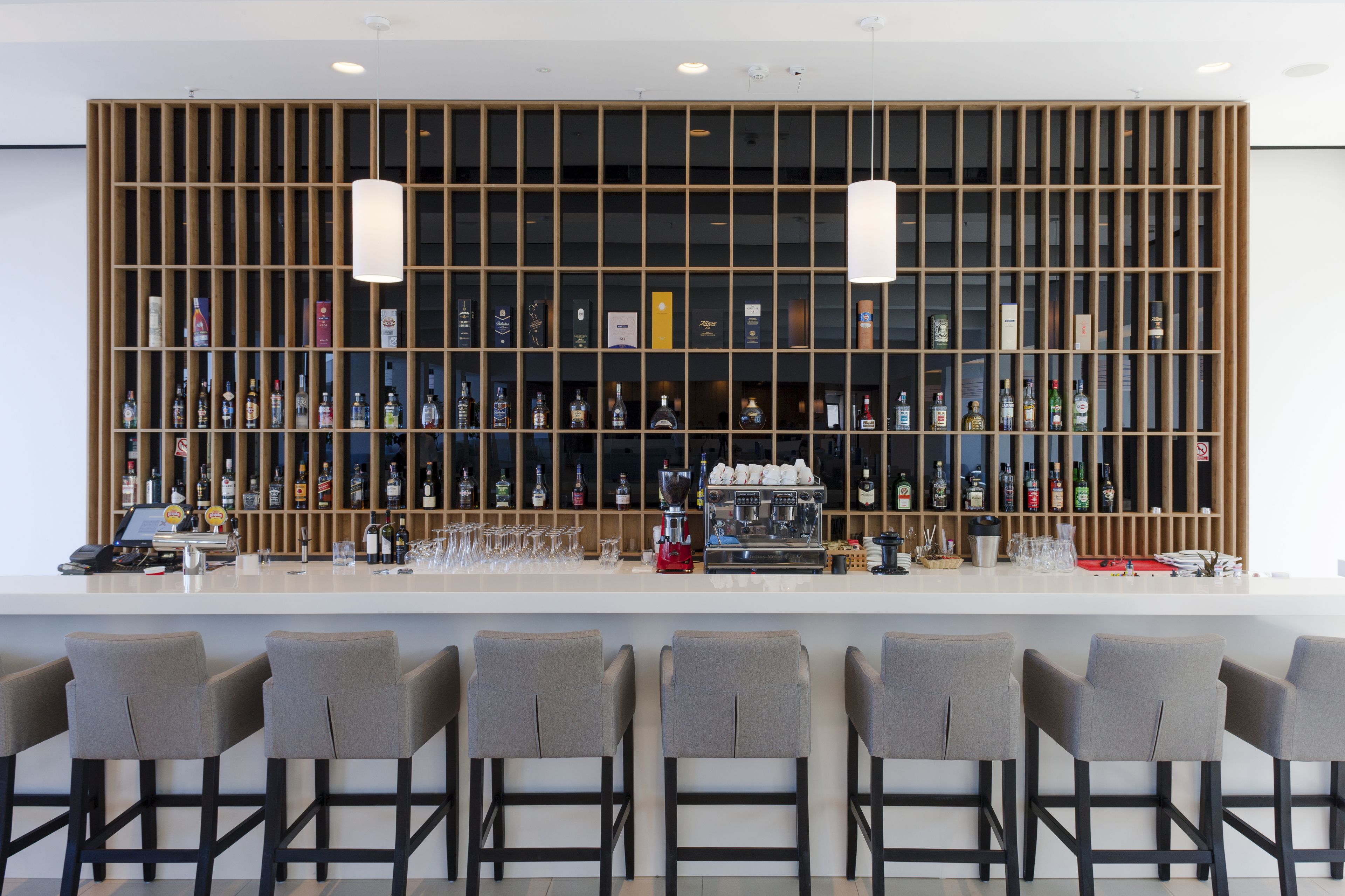 Eine moderne Bar mit einer langen Theke, mehreren Barhocker und einer Auswahl an Spirituosen.