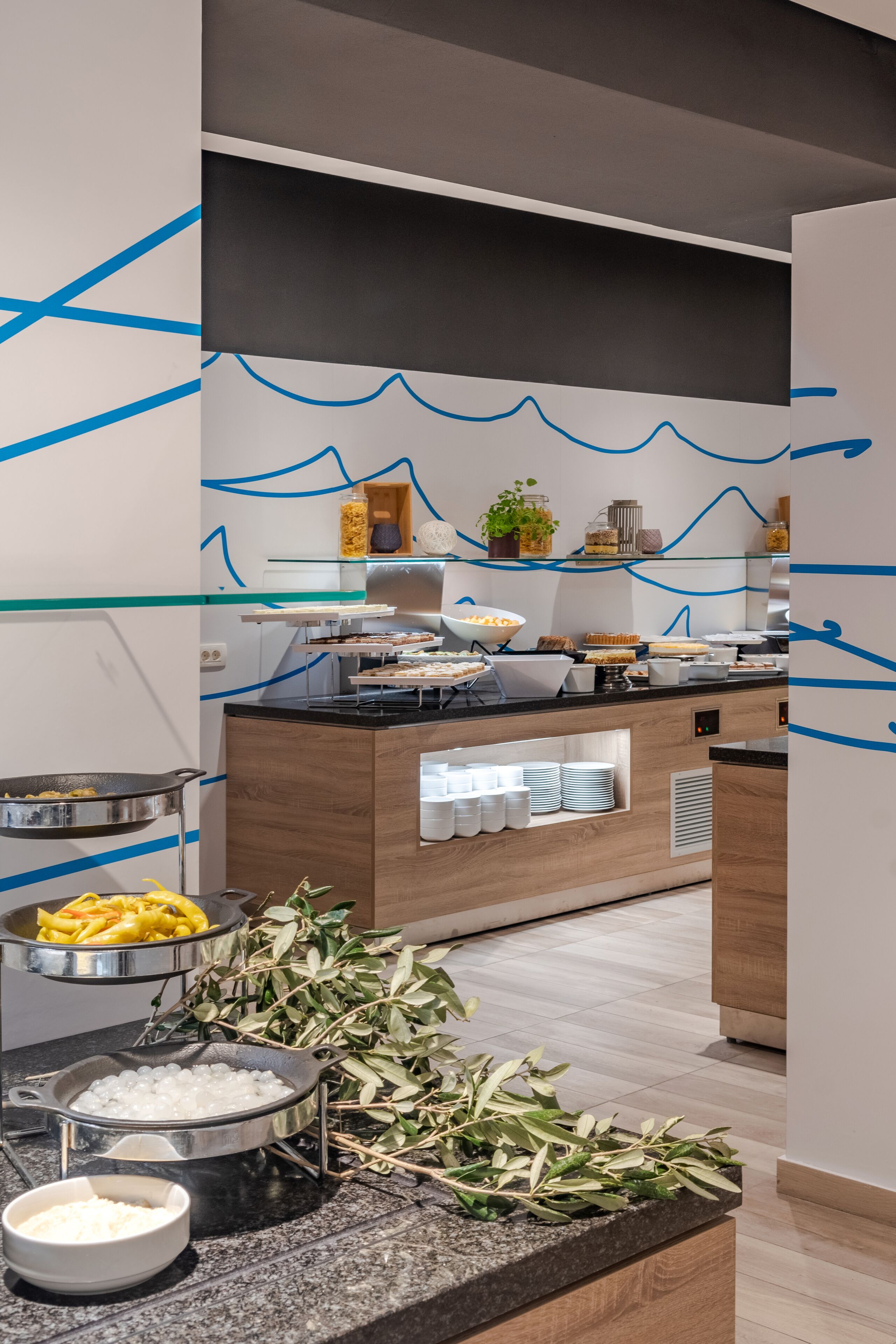 A modern kitchen area with a buffet setup, including various food items and a coffee station.