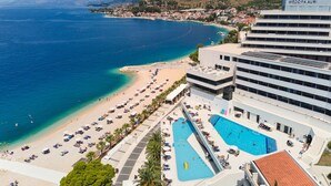 A coastal hotel with a pool, beach, and mountain views.