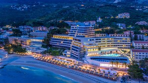 A coastal hotel with multiple buildings, a beach, and a pool area.