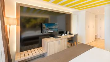 Una habitación de hotel moderna con una televisión montada en la pared, un escritorio con una silla, una cama y un banco de madera.