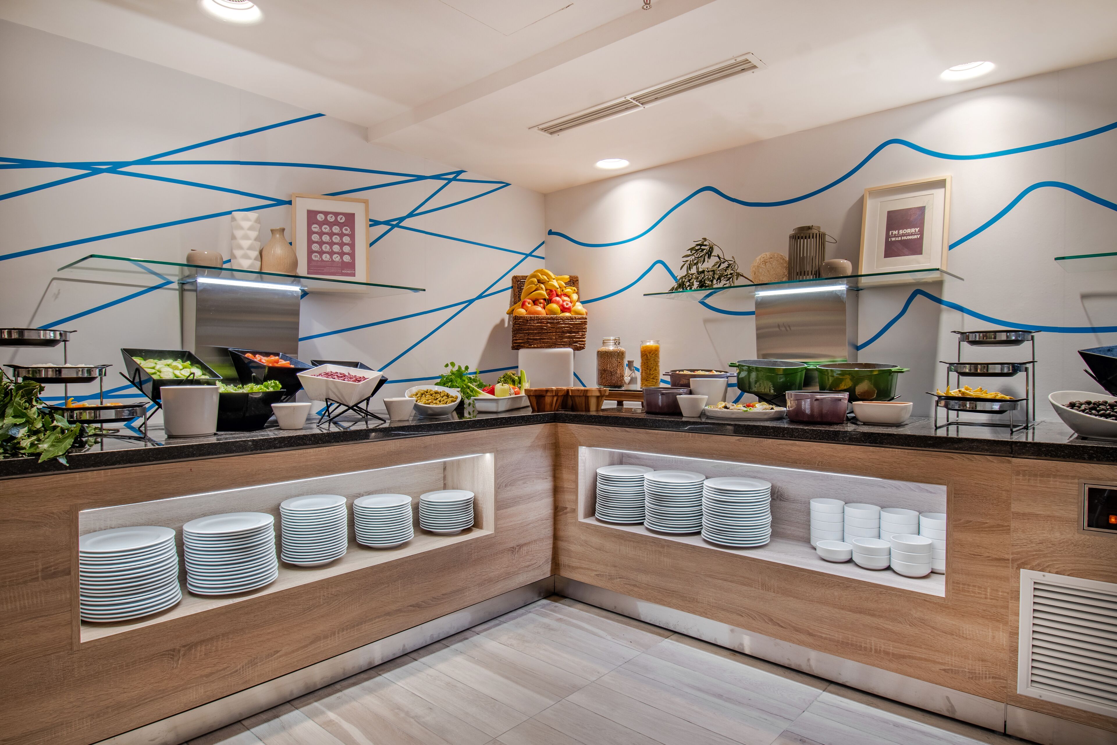 Une cuisine moderne dotée d’un îlot central, d’étagères intégrées pour ranger les assiettes et de divers produits alimentaires exposés sur le plan de travail.