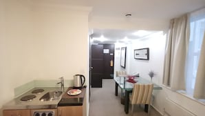 Cocina compacta con estufa, lavamanos y un pequeño comedor con mesa y sillas.