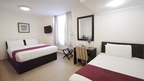 Habitación de hotel con dos camas, un escritorio, una silla, un televisor y una ventana con cortinas.