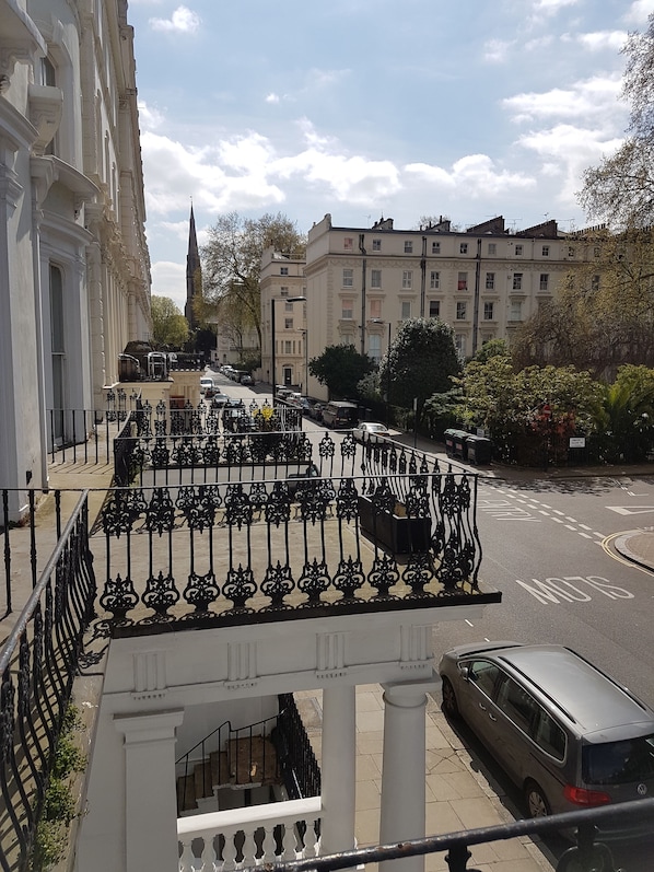 A street view with a white building featuring ornate iron railings and a staircase leading to an upper level. - The Royale Chulan Hyde Park (London)