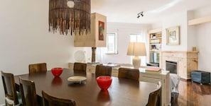 Un coin repas avec une table en bois, des bols rouges et un luminaire suspendu.