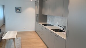 Eine moderne Küche mit grauen Schränken, einem Holztisch und einer gefliesten Spritzschutzwand.