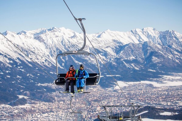 A ski lift with two skiers in blue and orange jackets. - Muttererhof (Mutters)