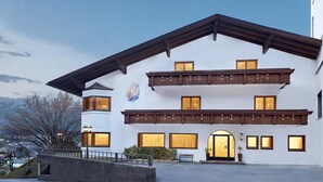 Ein mehrstöckiges Gebäude mit weißer Fassade, Holzbalkonen und großen Fenstern.