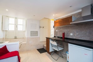 A compact kitchen with a black countertop, a built-in oven, and a small refrigerator.