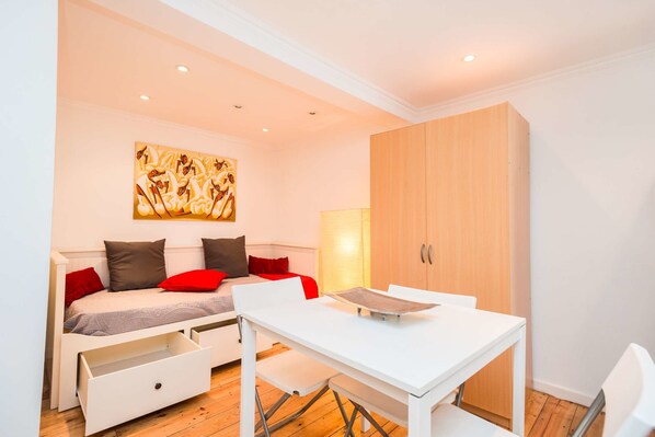 A modern bedroom with a bed, bedside tables, a desk, and a wardrobe.