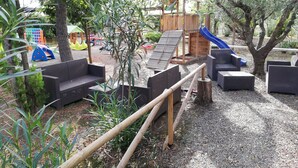 Zona de juegos infantiles con tobogán, estructuras de juego y asientos.