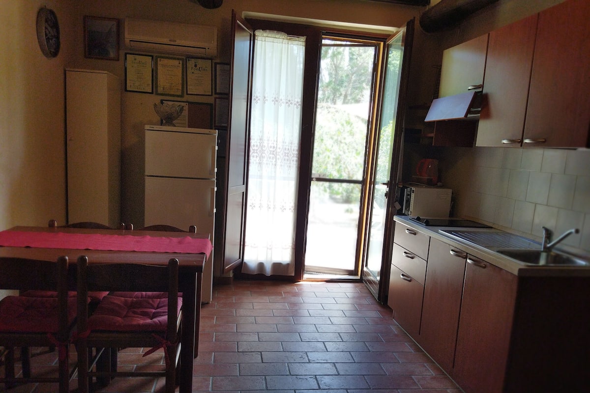 A compact kitchen with a dining table, chairs, a refrigerator, and a sink.